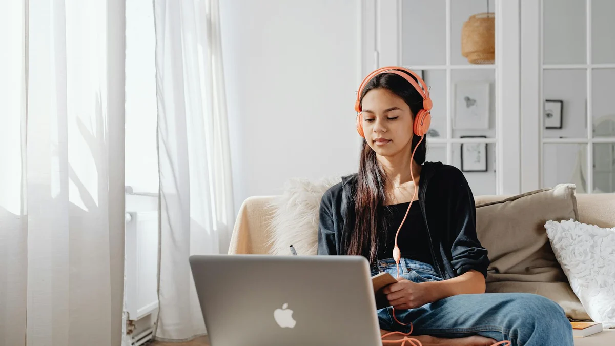 Persona estudiando inglés online con laptop y auriculares en casa